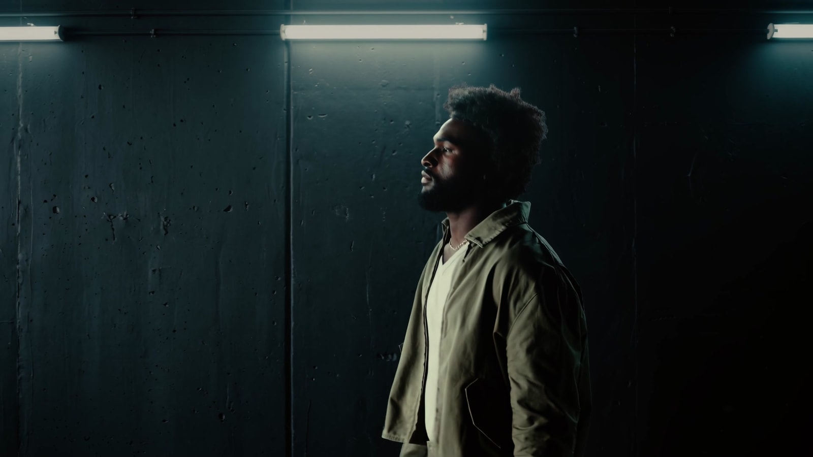 Will Anderson Jr. in profile beneath a fluorescent light in a dark tunnel.