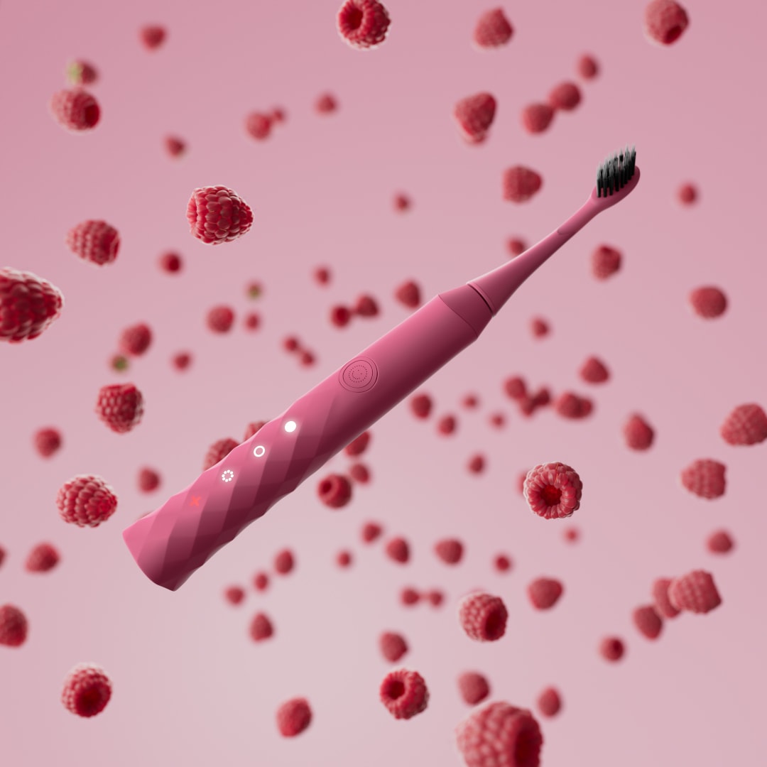 A pink Burst toothbrush floats among raspberries against a pink background.