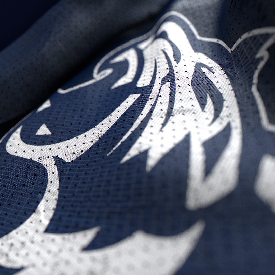 Close-up of a white bird emblem on dark jersey fabric.