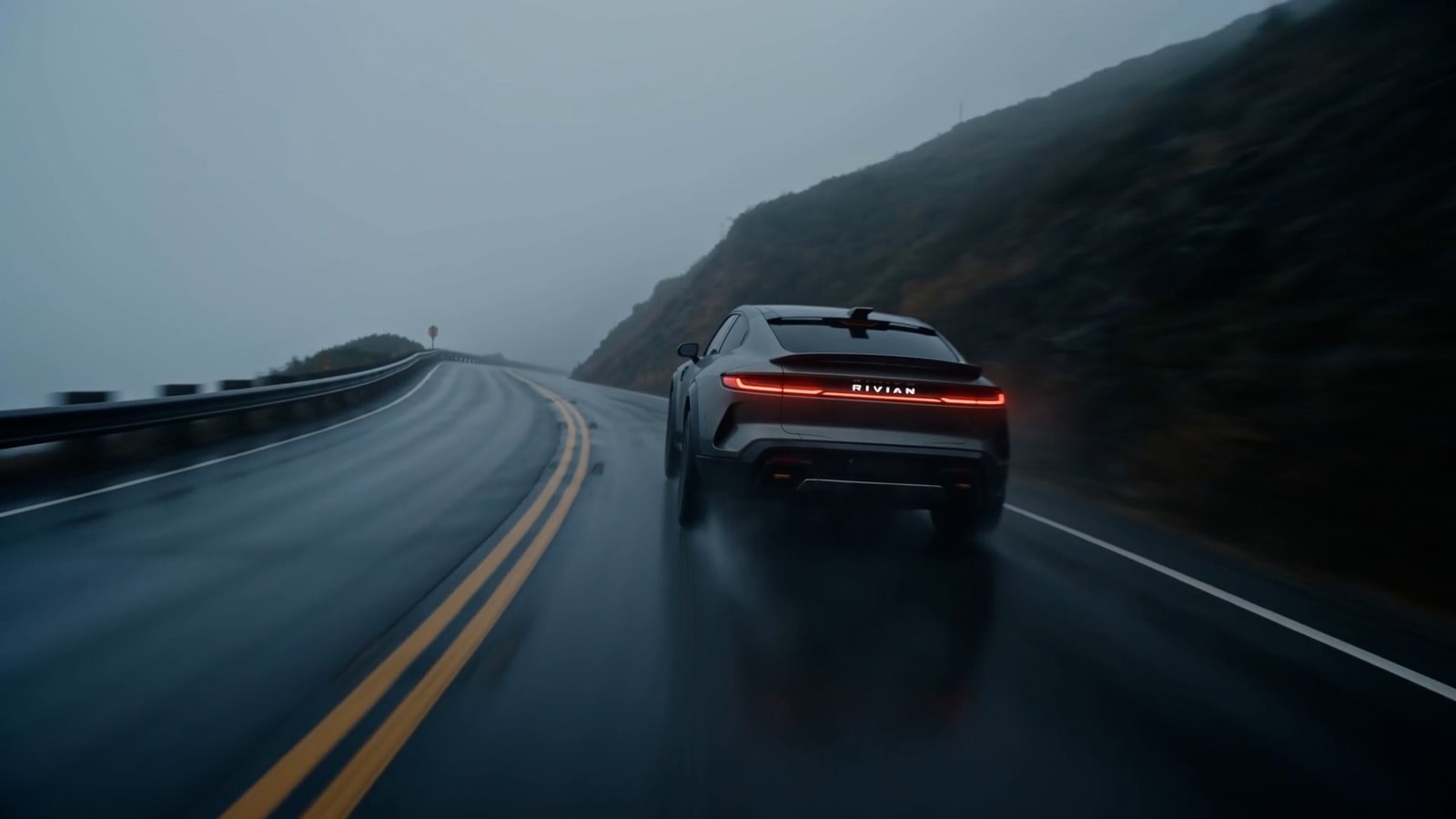 Finished silver sports car on a wet mountain road.