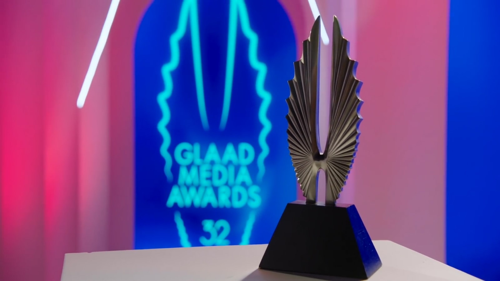 A GLAAD trophy in front of colorful 32nd GLAAD Media Awards graphics.