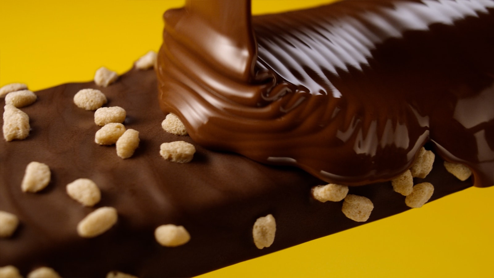 Chocolate pours over a Fulfil bar with scattered crisp pieces.