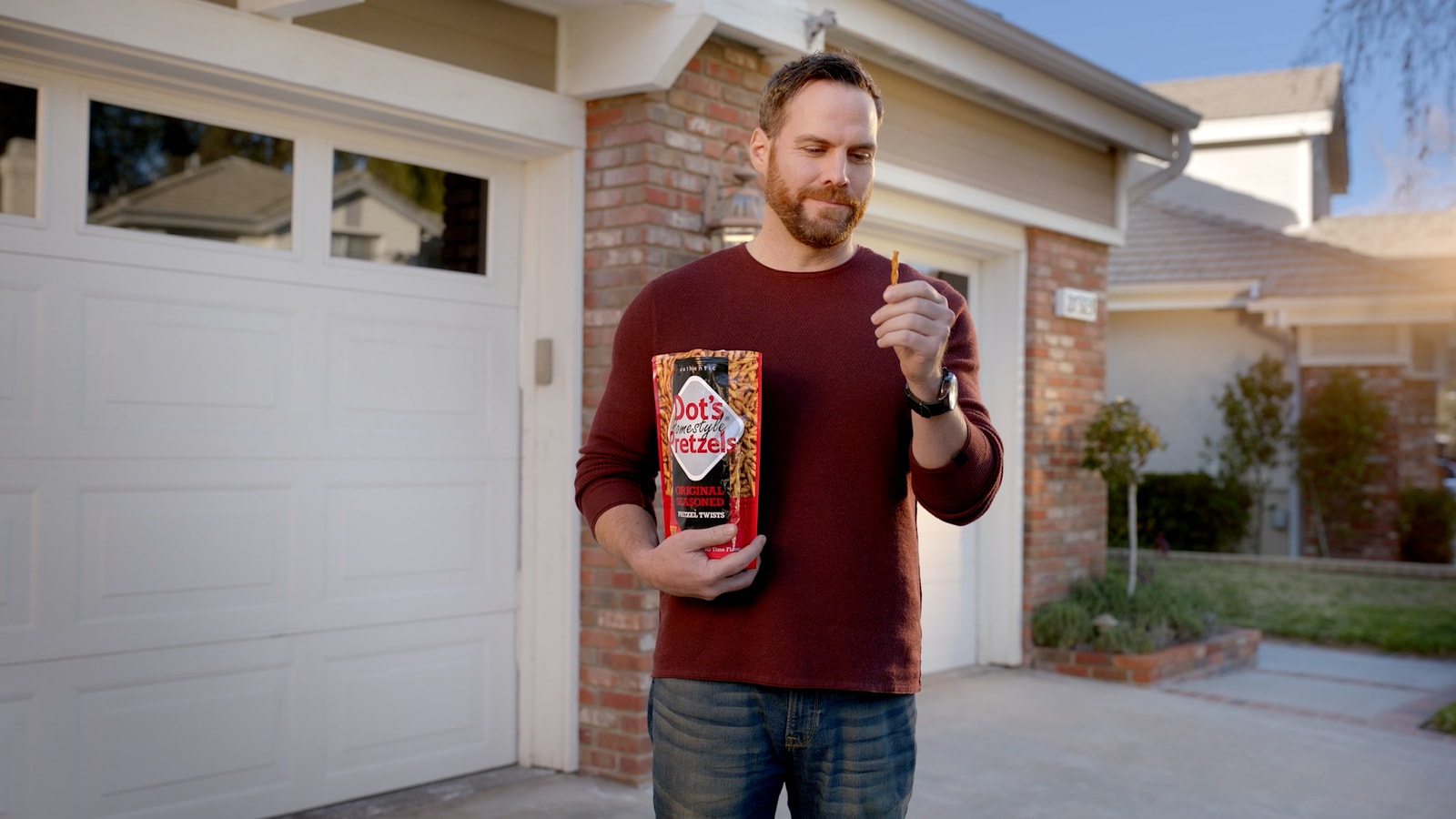A man holds Dot’s pretzels outside a suburban home.