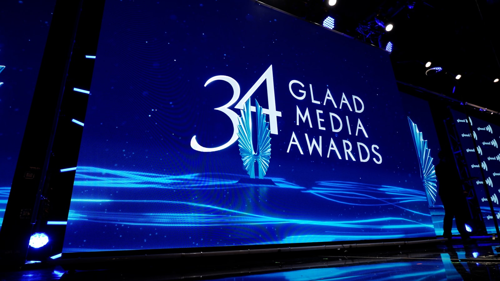 The 34th GLAAD Media Awards logo above an electric-blue reflective surface.