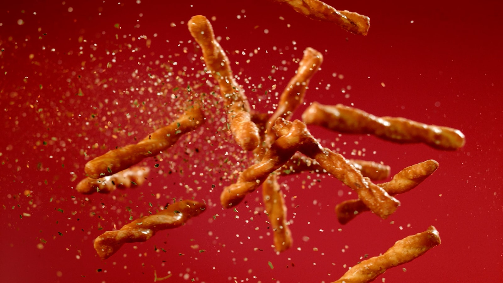 Dot’s pretzel twists and seasoning fly across a red background.