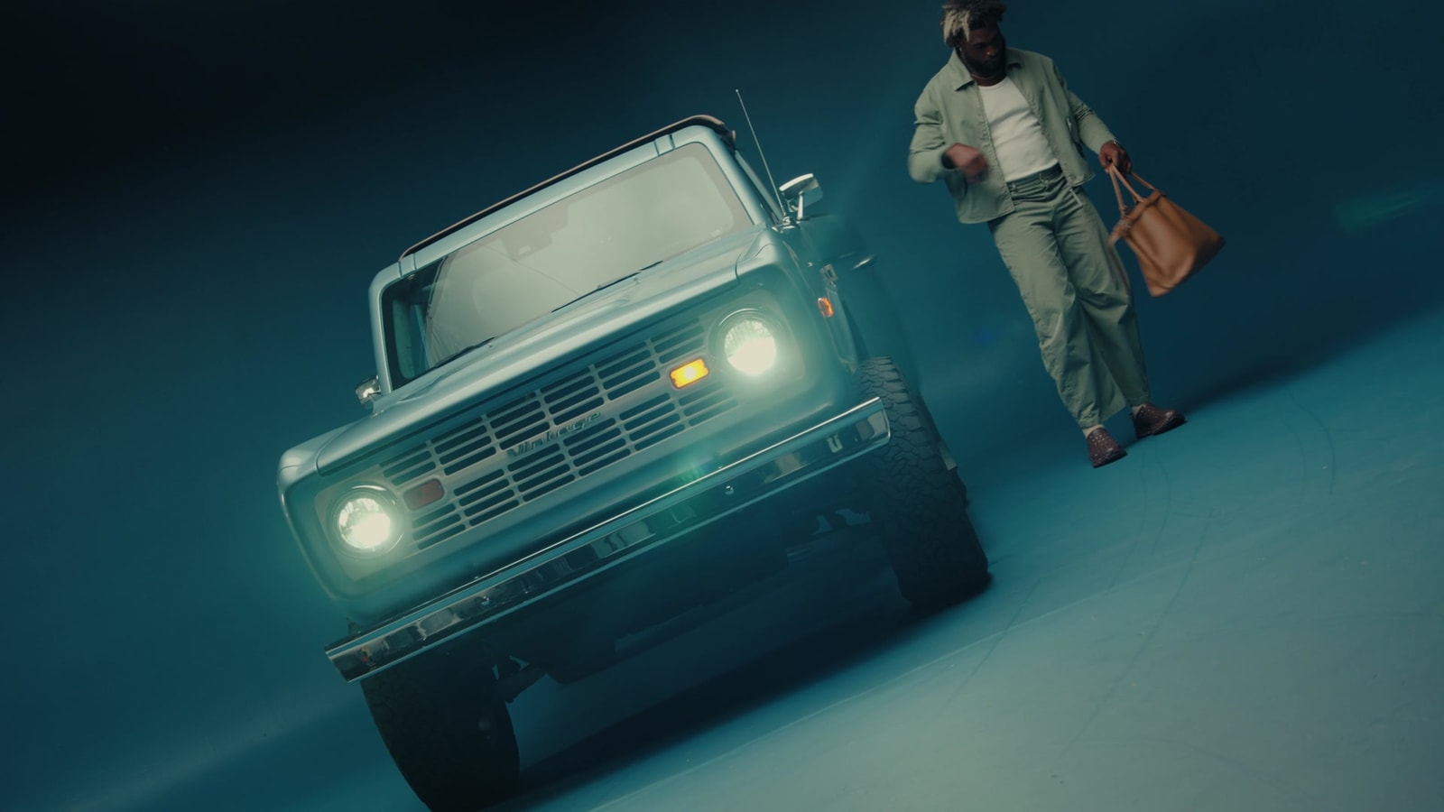 Will Anderson Jr. stands beside a pale blue vintage truck on a blue studio set.