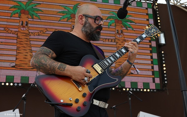 A guitarist performs in front of colorful cactus animation.